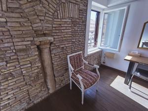 a chair in a room with a brick wall at The little column in Rome