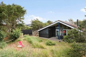 a small black house with two red chairs in front of it at LN1965-Hirtshals-Klinken-11 in Hirtshals +15 photos