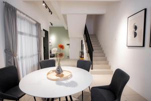 a white dining room with a white table and chairs at The Cove Hillside Residence Ipoh by PLY Home in Ipoh