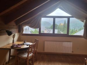 a dining room with a table and a large window at Ático dúplex Casa Ximet in Benasque