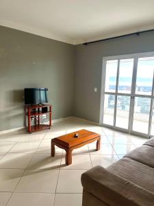 Cobertura Vista Mar com Piscina Privativa - PG في برايا جراندي: غرفة معيشة مع أريكة وطاولة قهوة