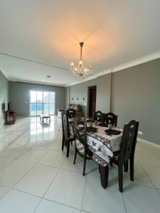 Cobertura Vista Mar com Piscina Privativa - PG في برايا جراندي: غرفة طعام مع طاولة وكراسي وثريا