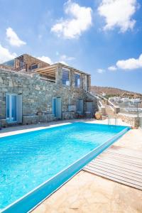 a villa with a swimming pool in front of a house at Natural Stone Villa II in Mýkonos City