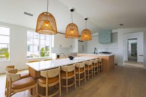 a kitchen with a large white island with bar chairs at The Joyrise House at Solaire Lunara Bay in Key West