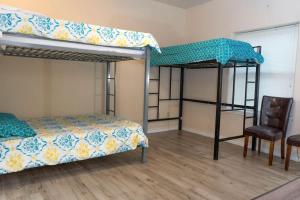 1 Schlafzimmer mit 2 Etagenbetten und einem Stuhl in der Unterkunft Ground Floor Condo with Pool unit A - Island Morning Sun 1 in South Padre Island