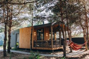 a house with a hammock in the middle of trees at Equi Lis - будиночки для відпочинку in Yasnogorodka