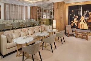 a living room with a couch and tables and chairs at Palacio de los Duques Gran Meliá - The Leading Hotels of the World in Madrid