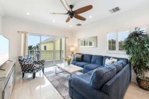 a living room with a blue couch and a ceiling fan at The Penthouse at The Cottages 2BR Oceanfront LUXE Condo in Old Isaacs