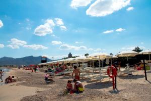 a group of people on a beach with umbrellas at Country & Beach B&B in Capoterra