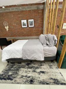 a bed in a room with a brick wall at Loft cerca de todo con cochera in León