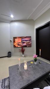 a room with a table with candles and a tv on the wall at شقه بغرفه وصاله ومطبخ باثاث انيق in Buraydah