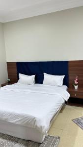 a large bed with a blue headboard and white sheets at شقه بغرفه وصاله ومطبخ باثاث انيق in Buraydah