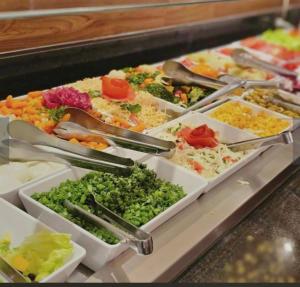 a buffet filled with trays of vegetables and ingrediants at FLAT 313 S4 Hotel in Brasília