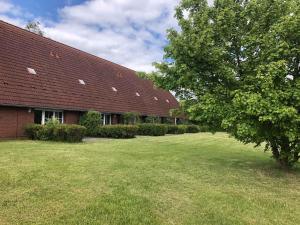 a red brick building with a large yard next to a tree at Pferdehof Ruhnau in Potzlow