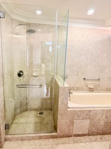 a bathroom with a shower with a tub and a glass door at Go Daily Service Suites Time Square kl in Kuala Lumpur