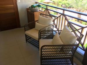 a balcony with two wicker chairs with white pillows at Ykutiba Imbassaí - Apartamento 2 Quartos - H104 in Imbassai