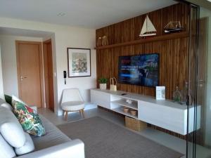 a living room with a couch and a tv at Ykutiba Imbassaí - Apartamento 2 Quartos - H104 in Imbassai +38 photos