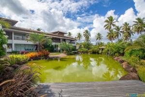 a pond in front of a building with palm trees at Ykutiba Imbassaí - Apartamento Superior - I104 in Imbassai