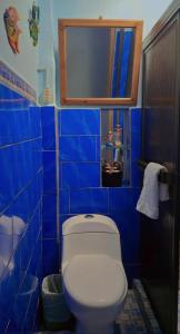 a blue tiled bathroom with a toilet and a mirror at Horizonte Nica Guest House in San Juan del Sur