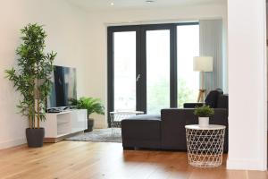 a living room with a black couch and some plants at Luxury 2-Bed Apt - Heart of Bham Free Parking in Birmingham