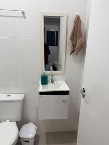 a white bathroom with a toilet and a sink at Oceanfront apartment with beautiful view in Palhoça