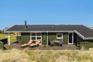ヒアツハルスにあるLN2015-Hirtshals-Raevestien-9のデッキに椅子とテーブルを設置した緑の家