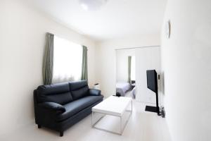 a living room with a black couch and a tv at Imari Russo Room 101 - Vacation STAY 16926 in Imari