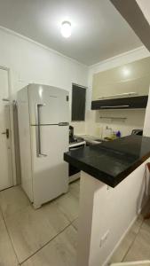 Il comprend une cuisine équipée d'un réfrigérateur blanc et d'un comptoir noir. dans l'établissement APTO 337 Malibu Praia Grande SP, à Praia Grande 6 autres photos