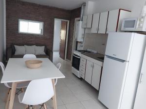 a white kitchen with a table and a white refrigerator at Pichincha departamento in Rosario