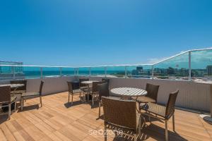 Un patio con mesas y sillas en un balcón. en SIP - Belos Estúdios em Salvador, en Salvador