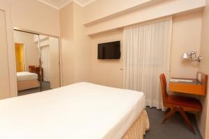 a bedroom with a bed and a desk and a television at Austral Express in Comodoro Rivadavia