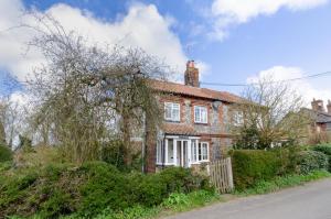 an old brick house on the side of a road at End Cottage in Letheringsett