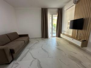a living room with a couch and a flat screen tv at Mias Apartment - Ilyonis Residence in Shëngjin
