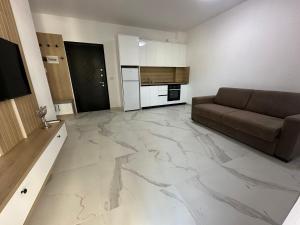 a living room with a couch and a kitchen at Mias Apartment - Ilyonis Residence in Shëngjin