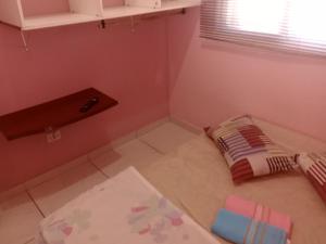 une petite pièce avec des murs roses et un sol blanc dans l'établissement Hostel & Cia Itanhaém, à Itanhaém