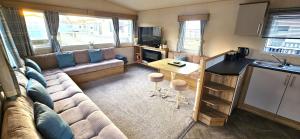 a living room with a couch and a kitchen at Abi Summer Breeze - West Sands in Selsey