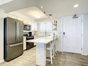 Il comprend une cuisine équipée d'un réfrigérateur et d'une table avec des chaises. dans l'établissement Beachfront Condo - OceanView, Pool & Steps to Flagler Ave, à Chicken Island