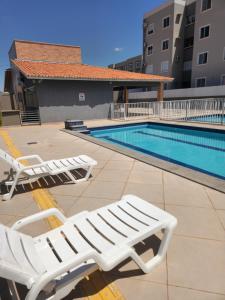 a pair of lounge chairs next to a swimming pool at Morada Aconchegante com 2 quartos and Sofá Cama in Imperatriz