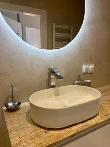 a sink in a bathroom with a large mirror at Apartament Sady in Busko-Zdrój +4 photos