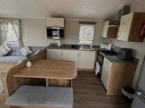 a small kitchen with a wooden table in a caravan at Southview caravan park in Winthorpe +1 photo