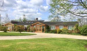 an exterior view of a house with a driveway at Romantic colonial lodge with hot tub in Baddiley