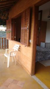 une chaise blanche assise sur le porche d'une maison dans l'établissement Suites da Cla - Suite 1, à Lima Duarte