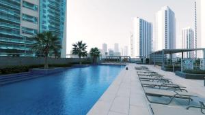 a swimming pool on the roof of a building with chairs at Panoramic Seaview one-bedroom apartment in Abu Dhabi