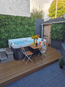 a hot tub on a deck with a table and chairs at JUNGLE HOT TUB, games room, near eateries, micro brewery, pubs, beauty salons and boutique shops, Argyle, free Netflix, in the heart of Plymouth - Dogs welcome - Hosted by Absolute Accommodation Plymouth in Plymouth