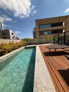 una piscina con una terraza de madera y una mesa en LK Santa Efigênia 2, en Belo Horizonte