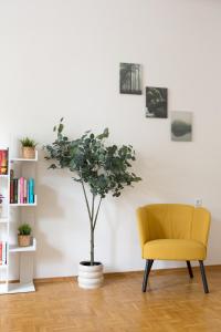 a yellow chair and a tree in a room at Bright City Apartment in Graz