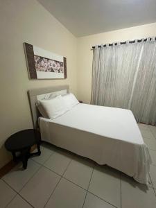 a bedroom with a white bed and a window at Casa da Nina in Louro Müller
