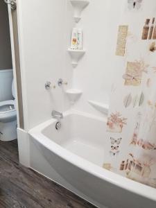 a white bathroom with a tub and a toilet at Gray Goose - Close to Falls & Casino in Niagara Falls