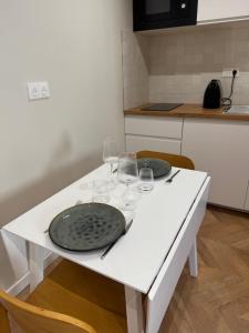 een witte tafel met twee borden en wijnglazen erop bij Studio cosy proche d Aix en Provence climatisé in Éguilles +11 foto's