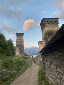 a dirt road next to a stone wall with two towers at Zhorzholiani House - Betkili in Lakhiri